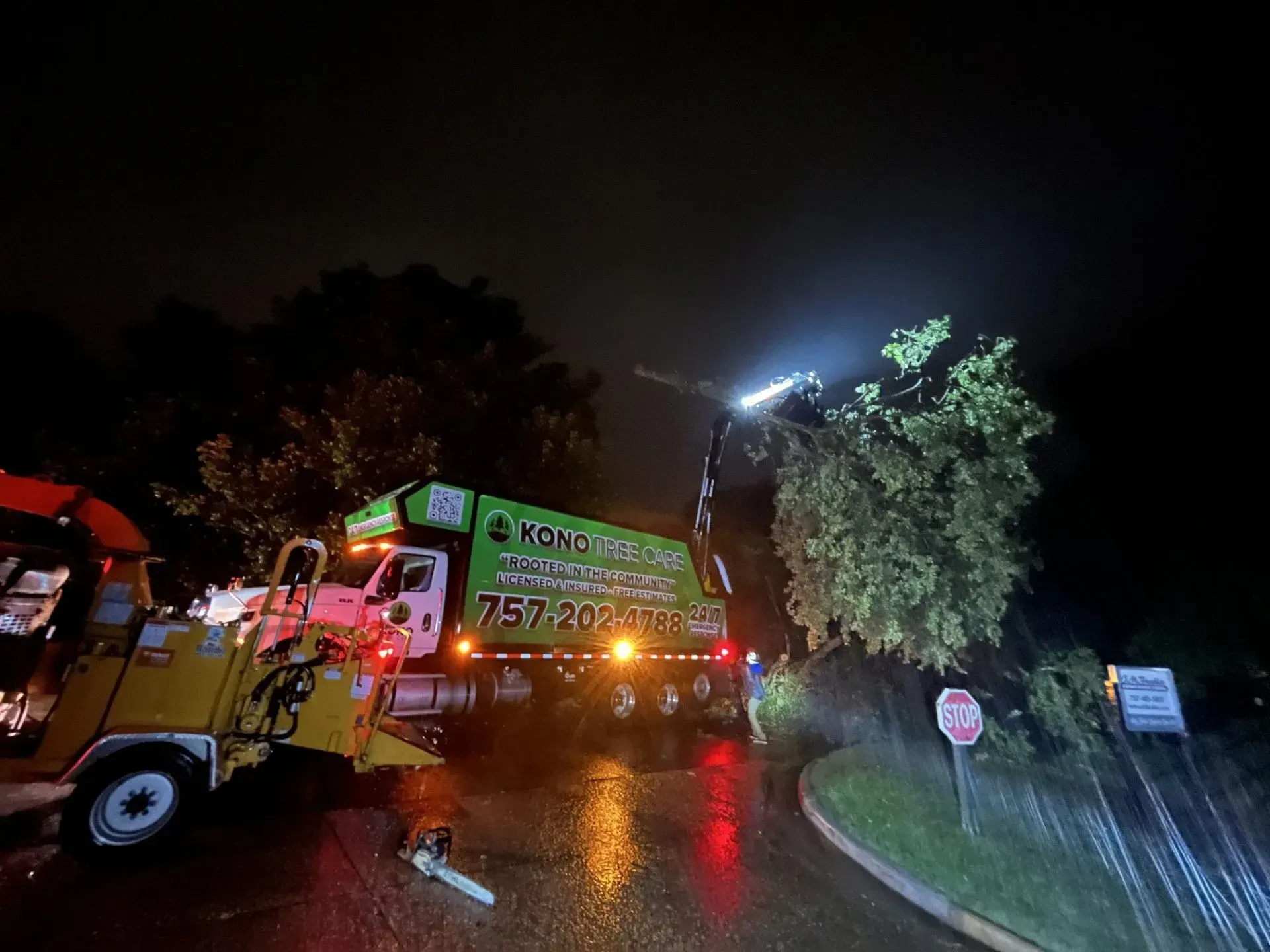 Nighttime roadside accident scene with tow truck and emergency lights on wet pavement