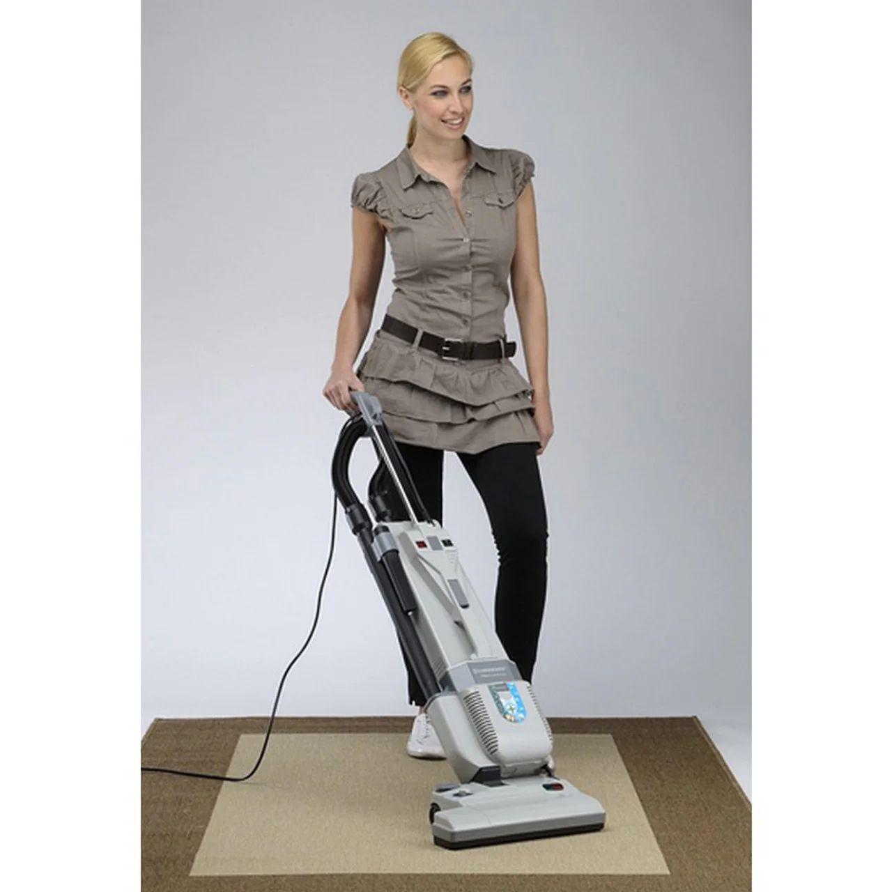 A woman is using a vacuum cleaner on a rug