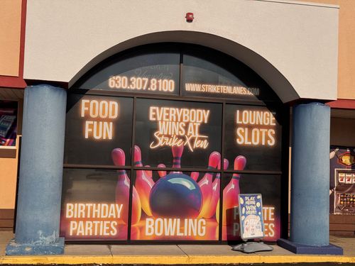 Bowling and entertainment center entrance with colorful signs for food, fun, lounge slots, and birthday parties