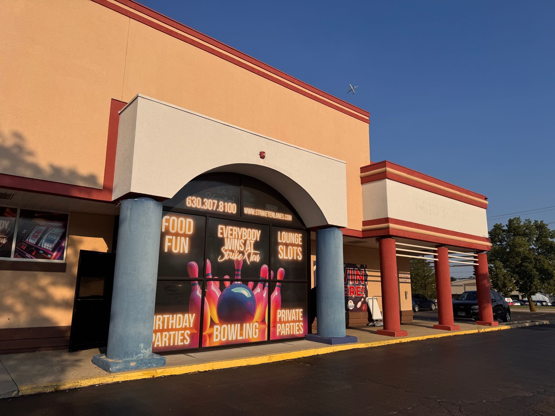 Storefront with Halloween signs and pumpkins in a shopping center parking lot