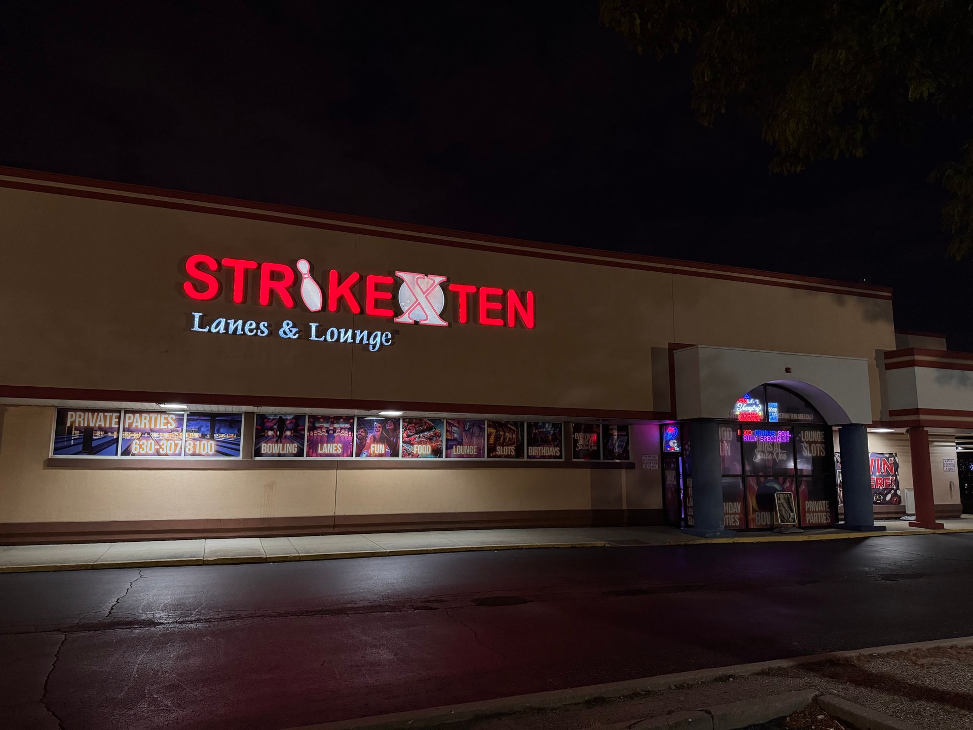 Night view of a Strike Ten Lanes & Lounge storefront with bright red sign and lit entrance