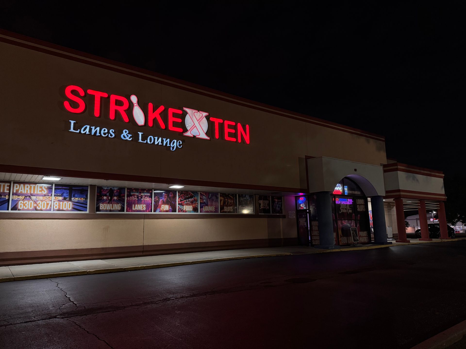 Exterior of Strike Ten Lanes & Lounge at night, with red neon signage and lit windows