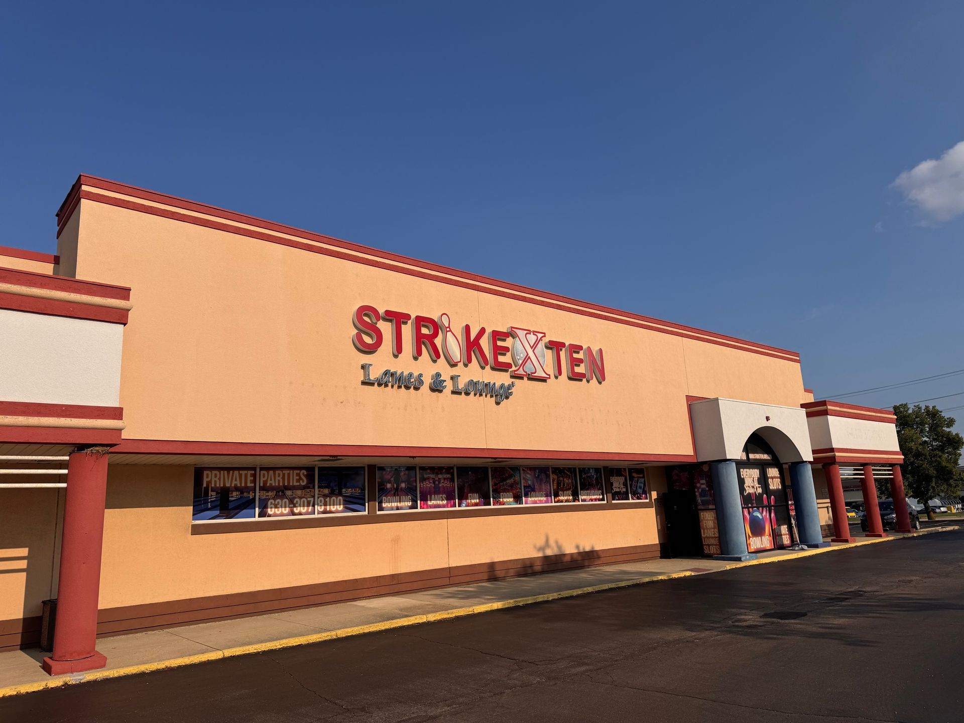 Bowling alley storefront with tan facade and red signage under a clear blue sky