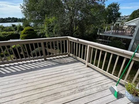 Wooden deck with railing overlooking a body of water and lush greenery.
