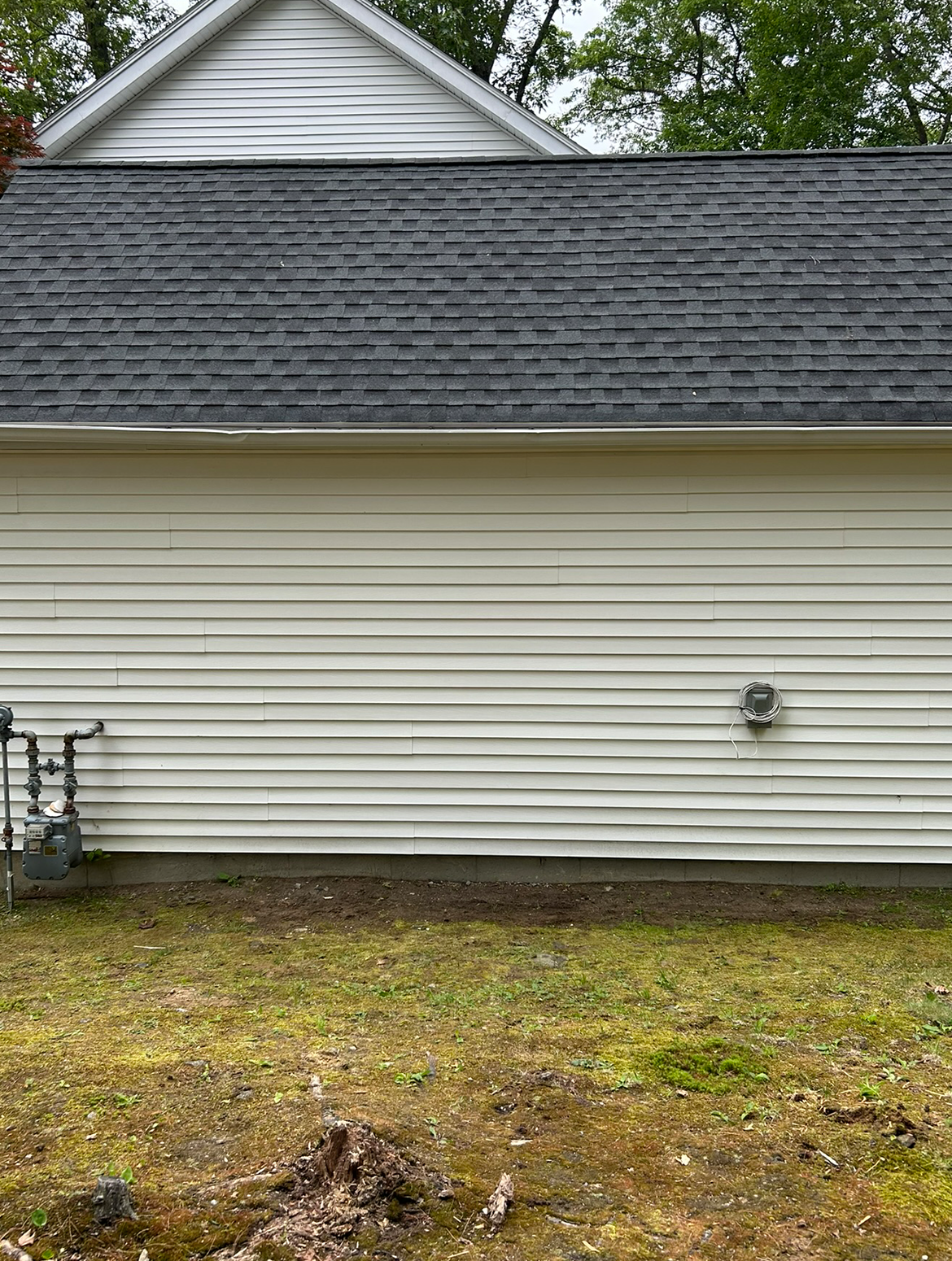 A white house with a black roof is sitting on top of a lush green field.