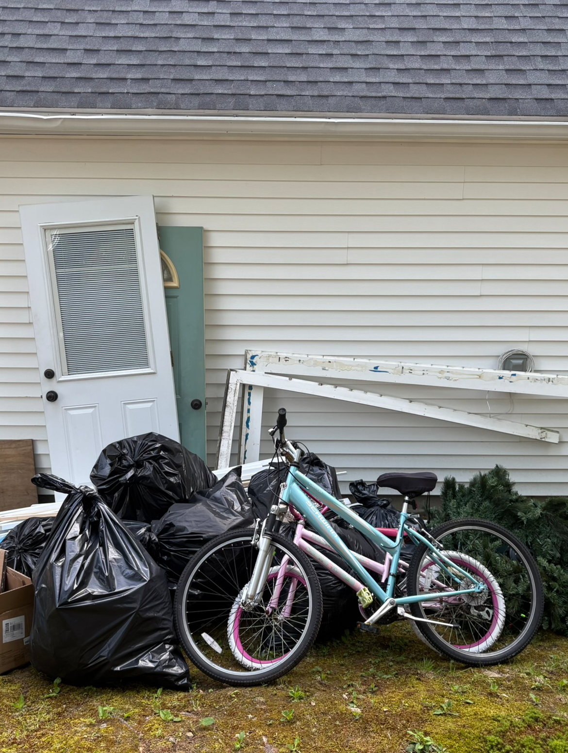 Two bicycles are parked in front of a pile of trash.