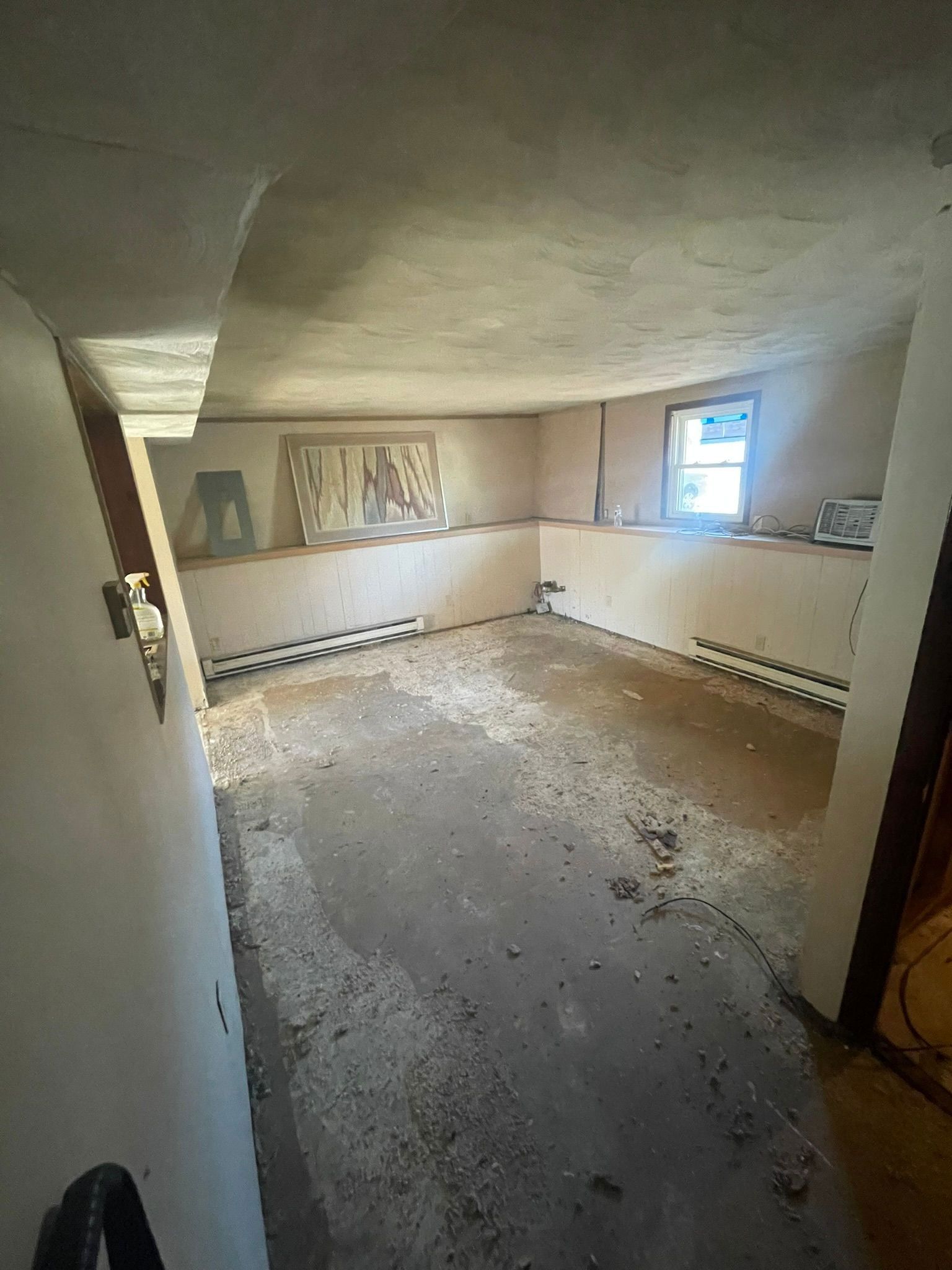 A room with a dirty floor and a window.