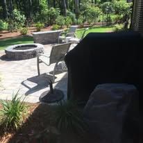 There is a fire pit on the patio with chairs and a grill.