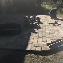 A man is laying bricks on a patio.