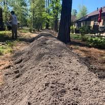 A pile of dirt is sitting next to a tree in a yard.