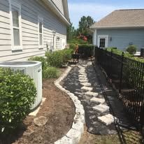 A stone walkway is being built in the backyard of a house.