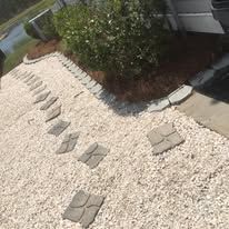 A walkway made of gravel and stone steps leading to a house.