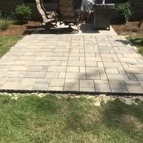 A patio with chairs and a grill in the backyard.