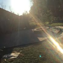 The sun is shining through a fence in a backyard.