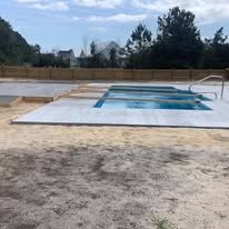 A large swimming pool is sitting in the middle of a dirt field.