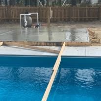 A swimming pool is being built next to a wooden fence.