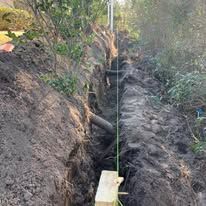 A wooden block is sitting in the middle of a dirt trench.