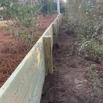 A wooden fence is sitting in the middle of a dirt path.