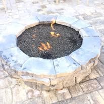 A fire pit is sitting on top of a brick patio.