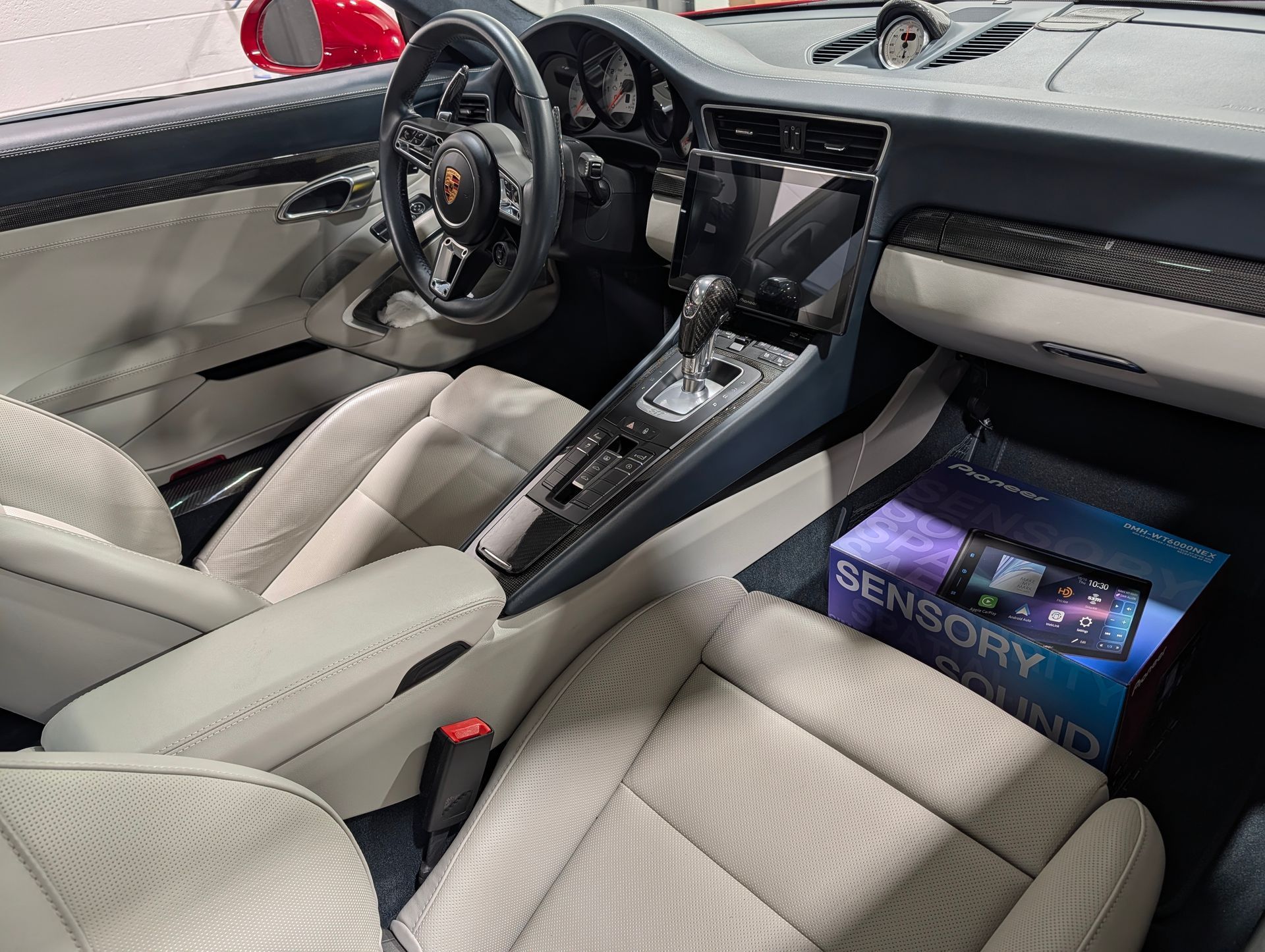 Luxury car interior with light leather seats, glossy center console, and dashboard display.