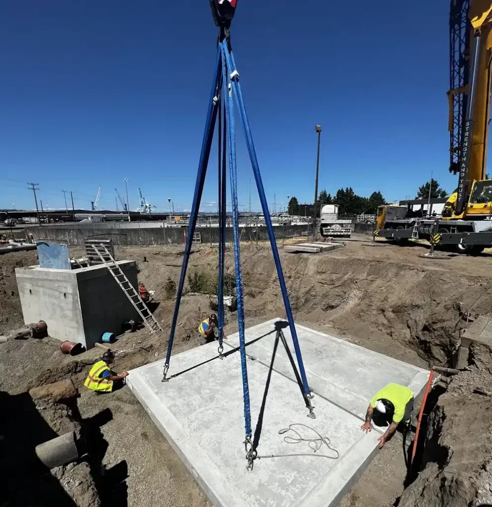 A construction site with a crane lifting a concrete slab.