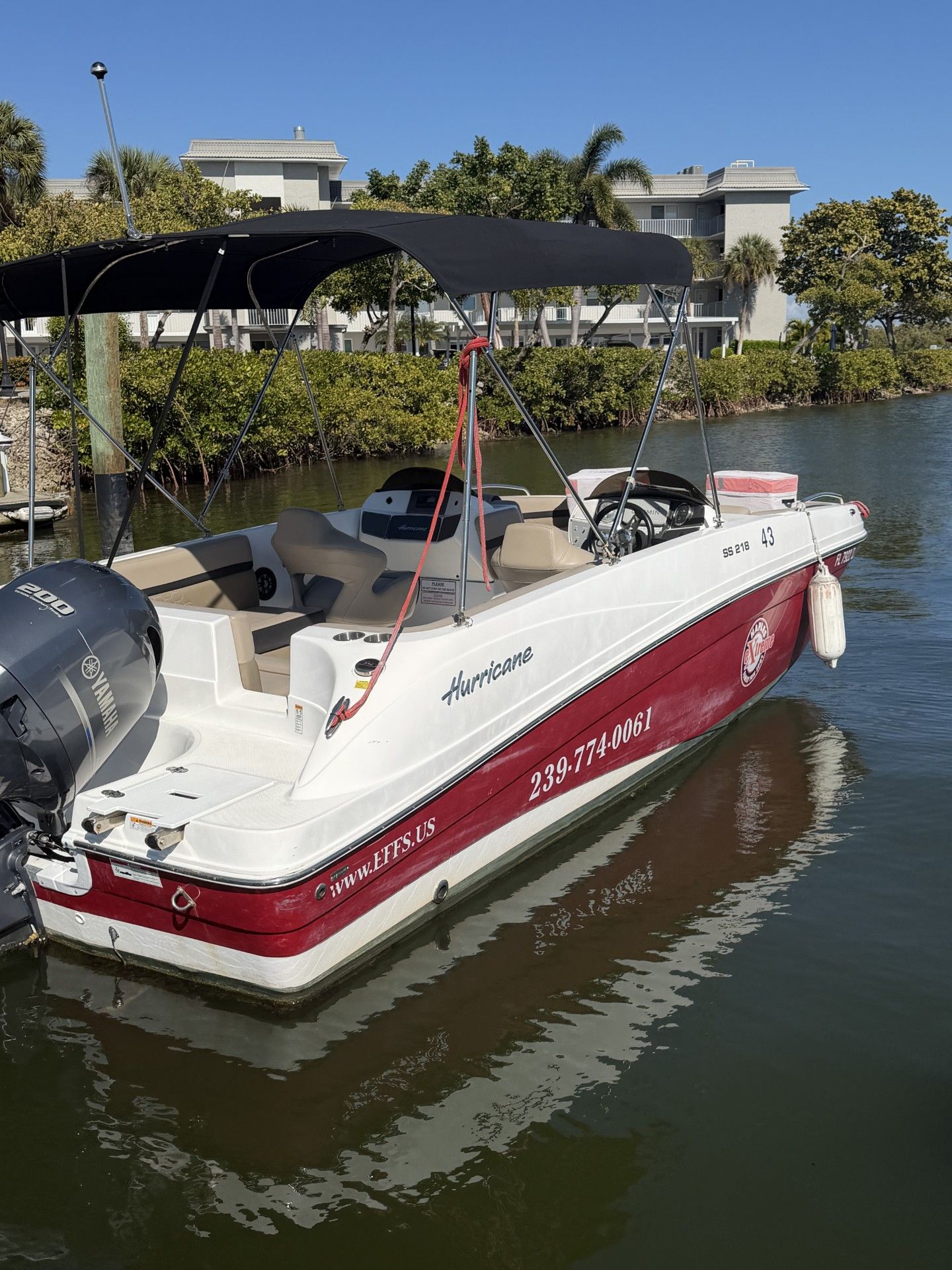 White and red motorboat named Hurricane docked in a canal.