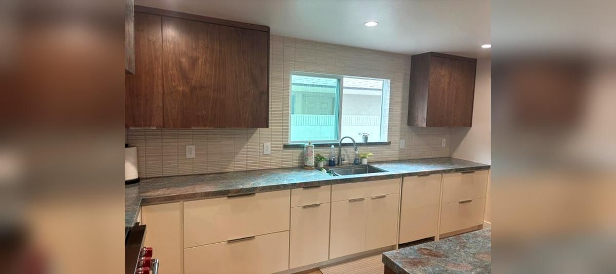 Kitchen with wood cabinets, beige counters, tiled backsplash, and a window over the sink.