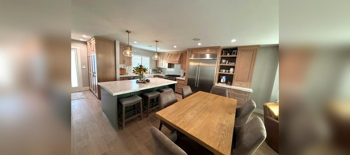 Modern open-plan kitchen and dining area with wooden table, island, and built-in shelves