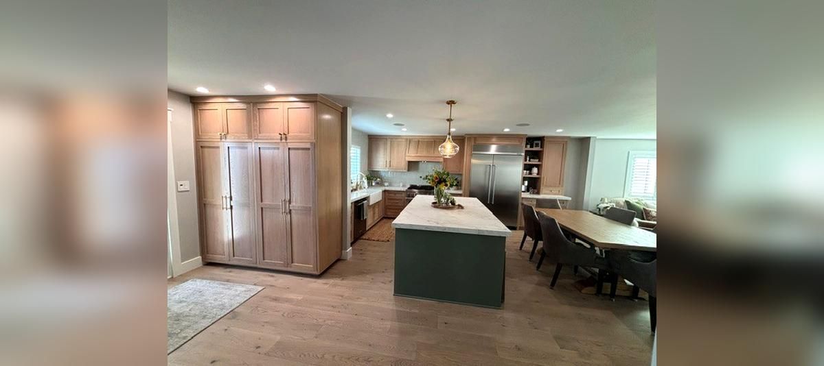 Bright kitchen and dining area with white cabinets, central island, and long table under pendant lights