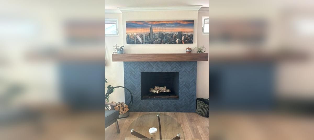 Cozy living room with a dark fireplace, mantle decor, and a framed landscape above it.