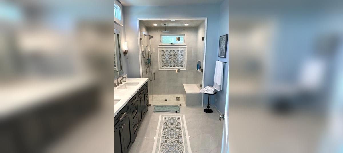 Bright bathroom with white vanity, tiled shower, and patterned runner rug.