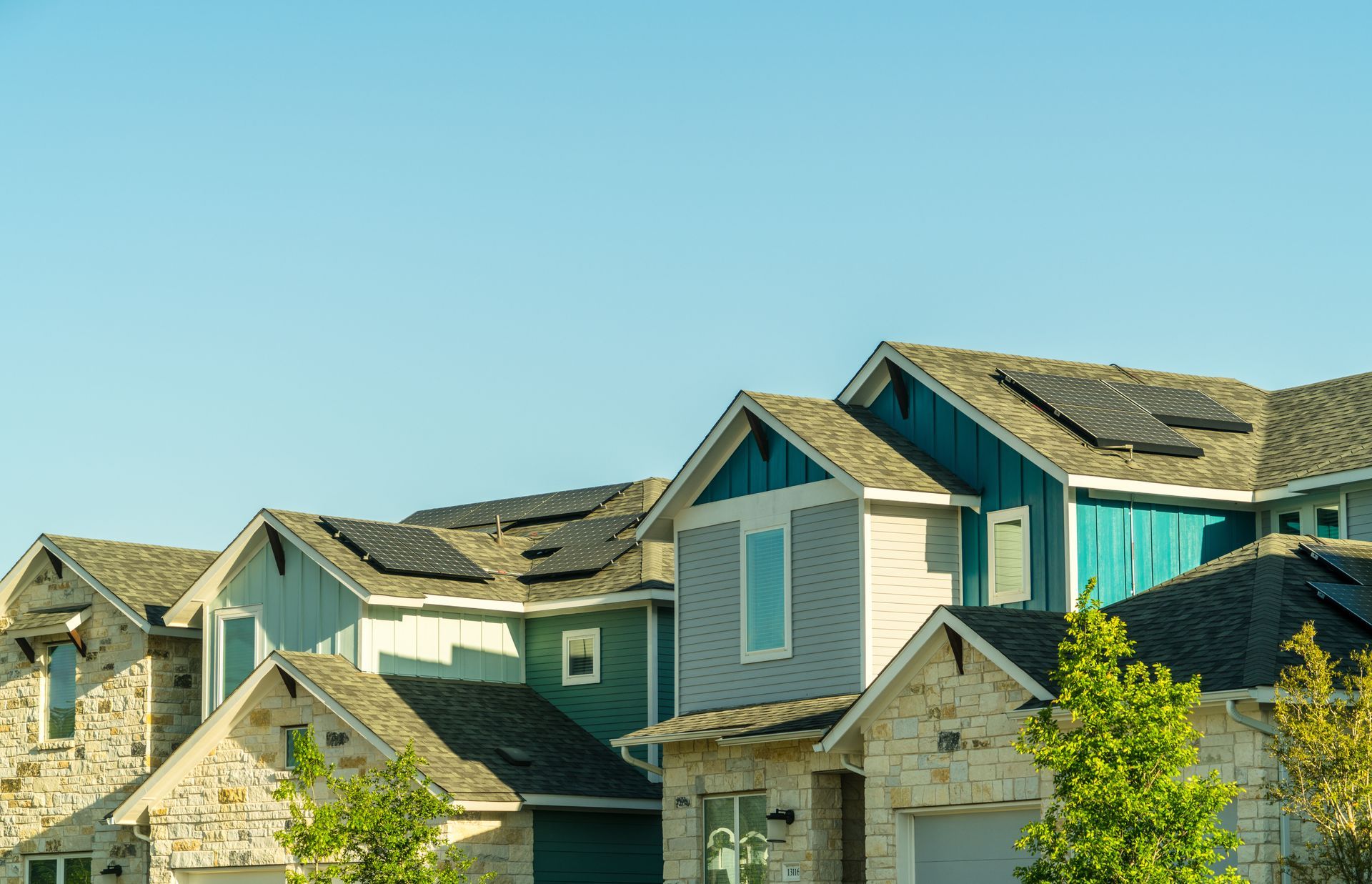 Row of colorful houses with solar panels on roofs against a clear blue sky.