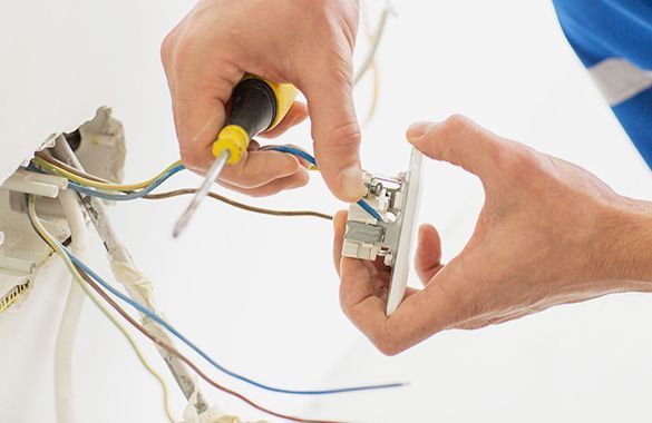 a person is fixing a light switch with a screwdriver