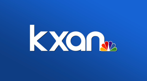 Kxan logo with white text on a blue background and a rainbow-colored peacock feather.