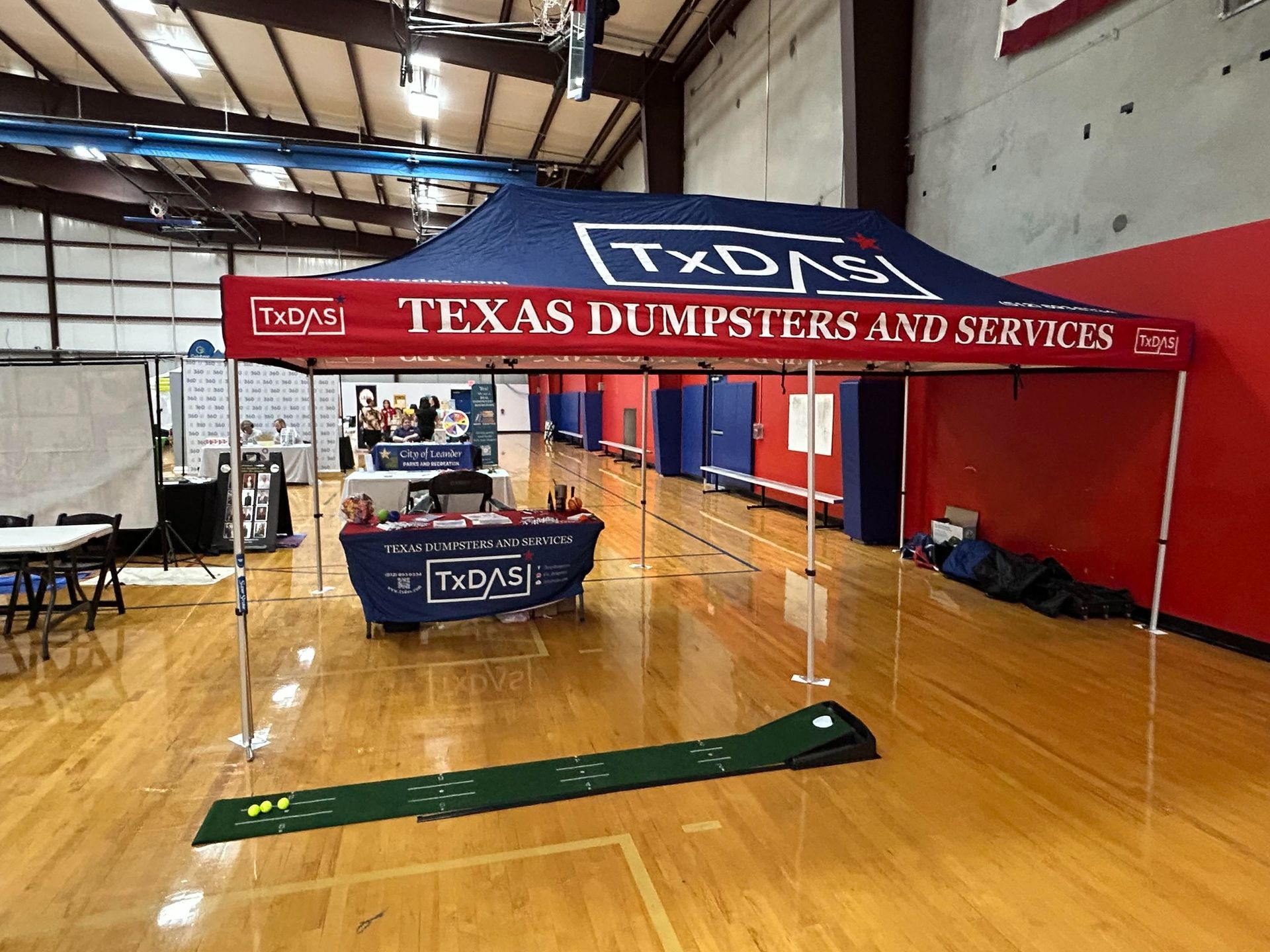 Texas Dumpsters and Services booth set up inside a gymnasium.