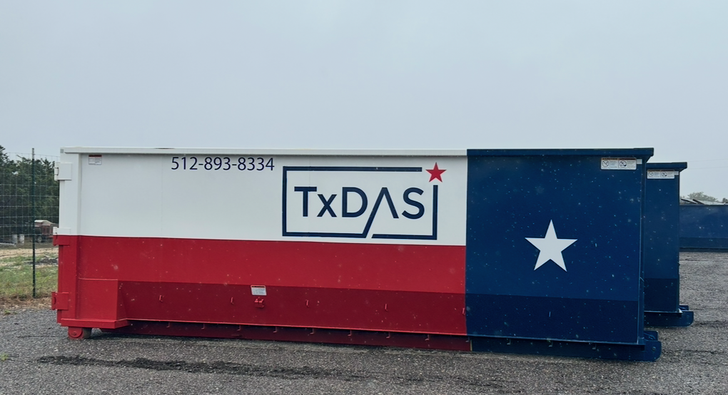 Roll-off dumpster painted as the Texas flag: white, red, and blue. The business name 