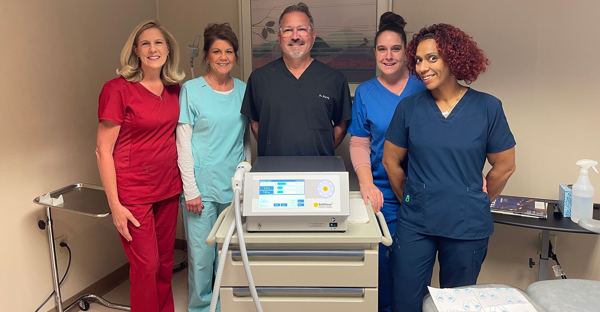 A group of nurses and doctors are posing for a picture in front of a machine.