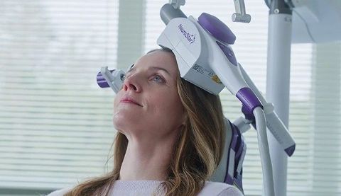 Woman wearing a white-and-purple headband device in a bright clinical setting