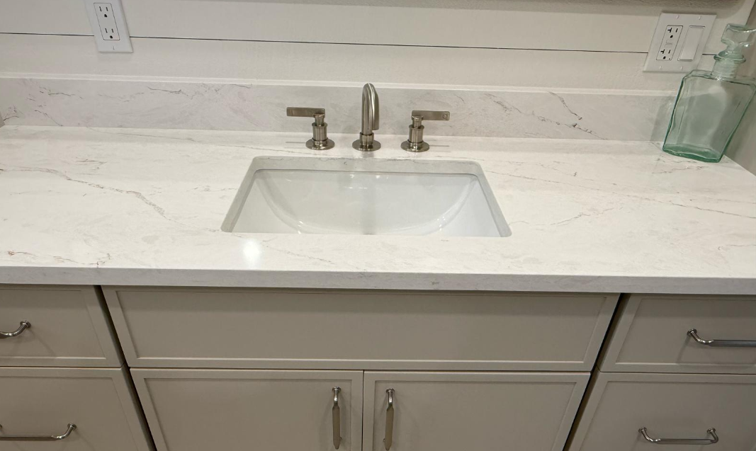 White bathroom vanity with sink, chrome faucet, marble countertop, and drawers below