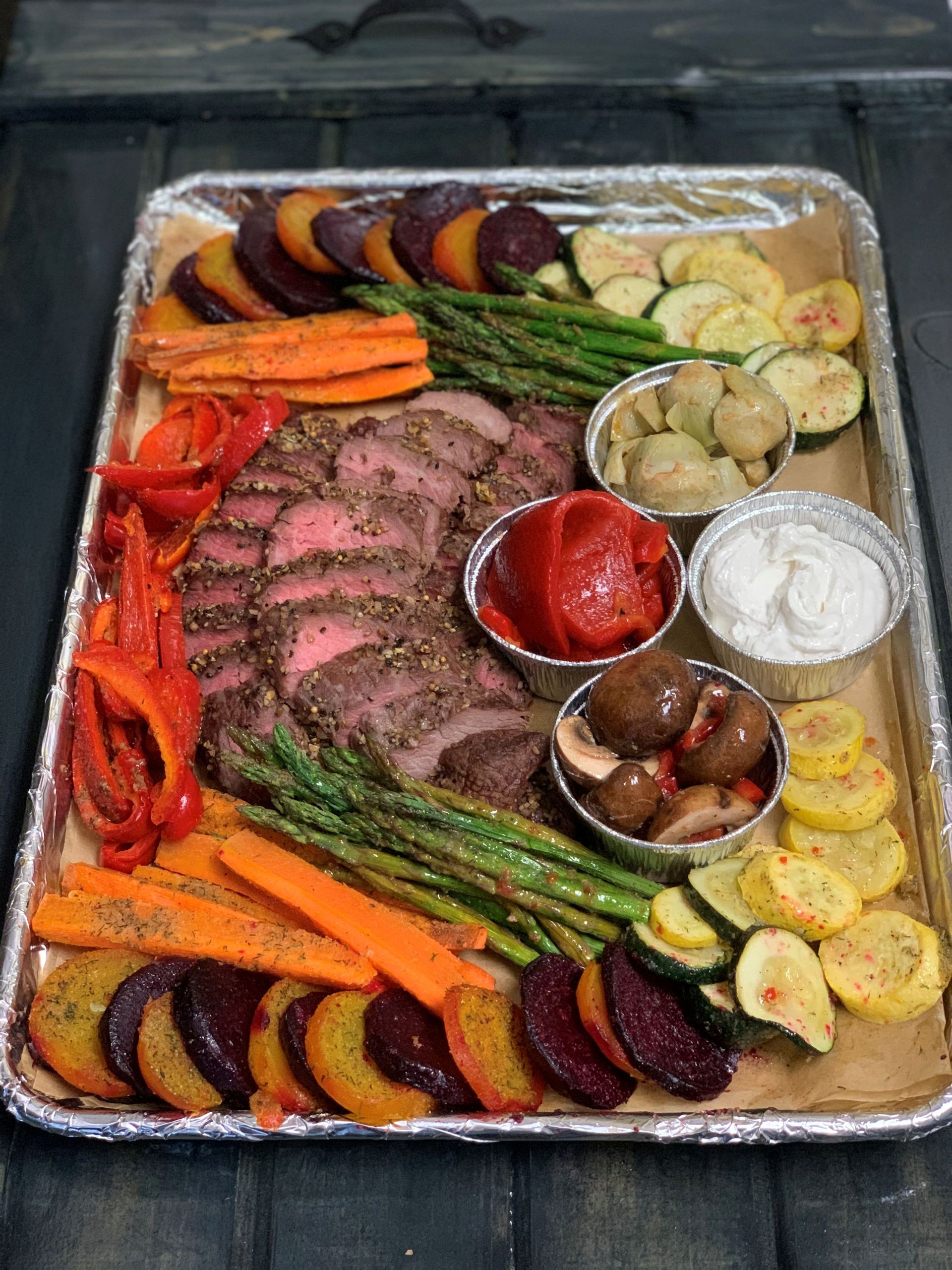 Roast beef platter with roasted vegetables: carrots, beets, squash, asparagus, peppers, and mushrooms, with dips.