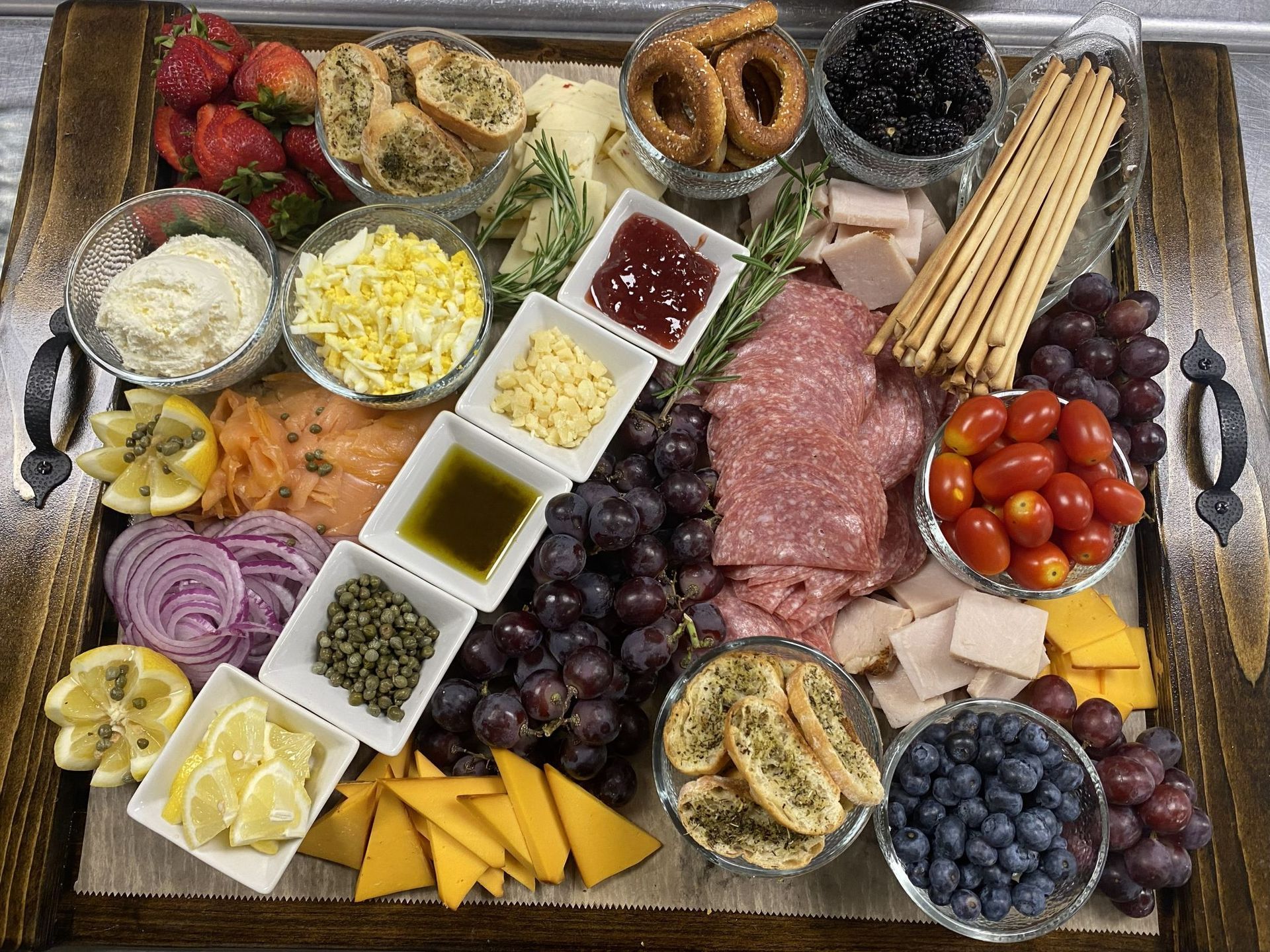Wooden charcuterie board with assorted cheeses, meats, fruits, crackers, and dips.