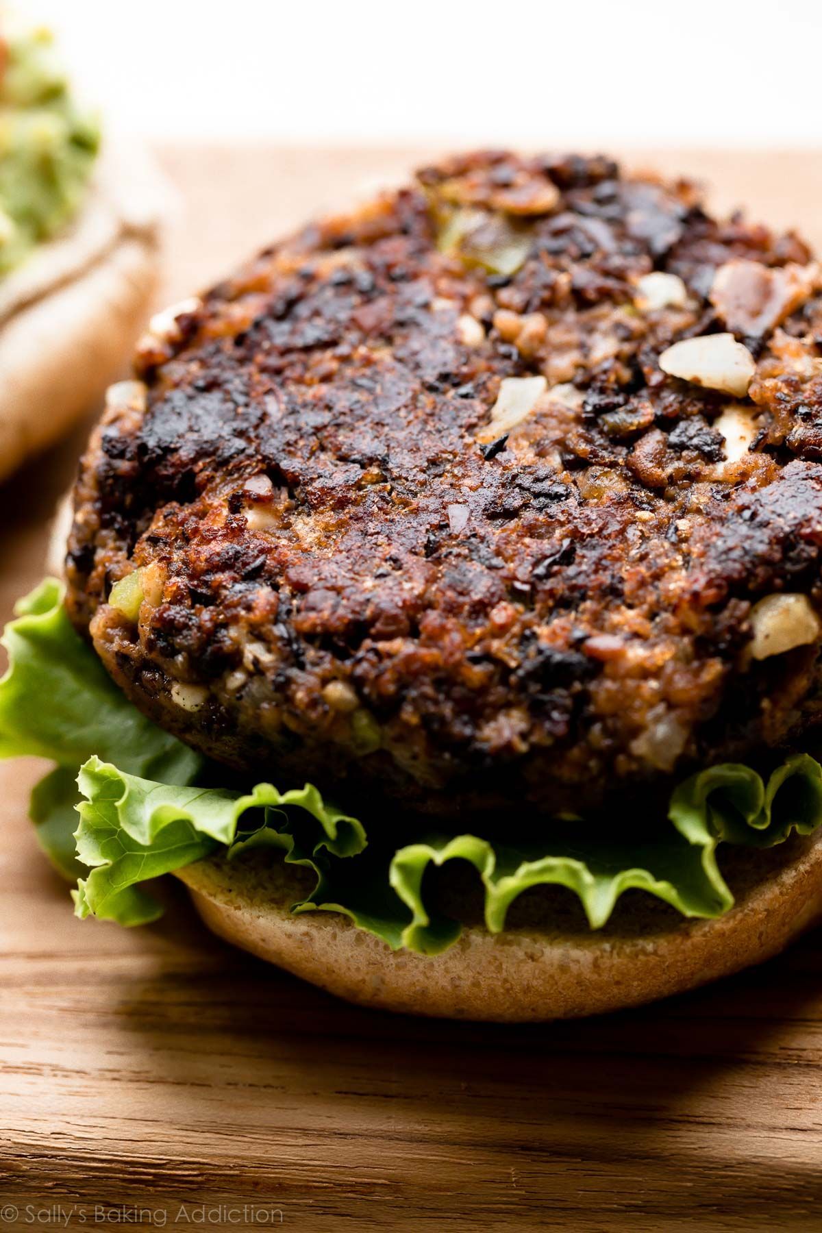 Black bean burger on a bun with lettuce, on a wooden board.