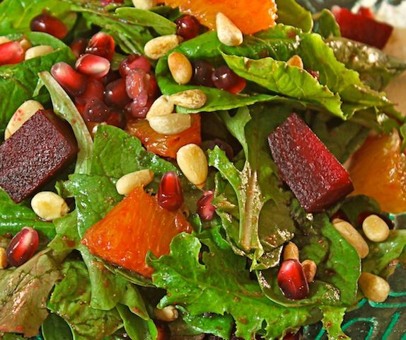 Salad with mixed greens, beets, oranges, pomegranate seeds, and nuts.
