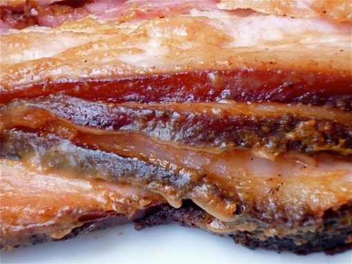 Close-up of layered roasted pork belly with crispy, golden skin and rich, fatty layers.