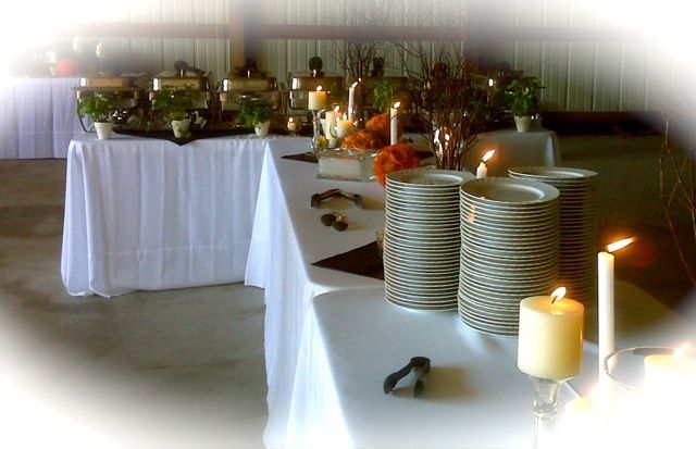 Buffet table set for a special event with food warmers, stacked plates, candles, and decorative elements.