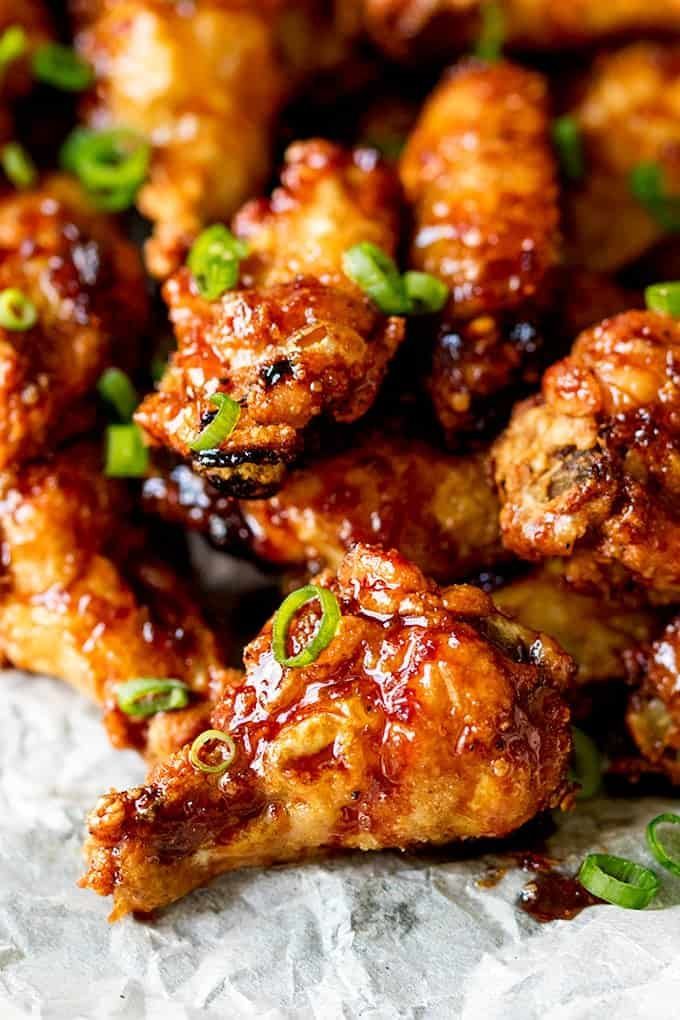 Pile of crispy glazed chicken wings, garnished with green onions.