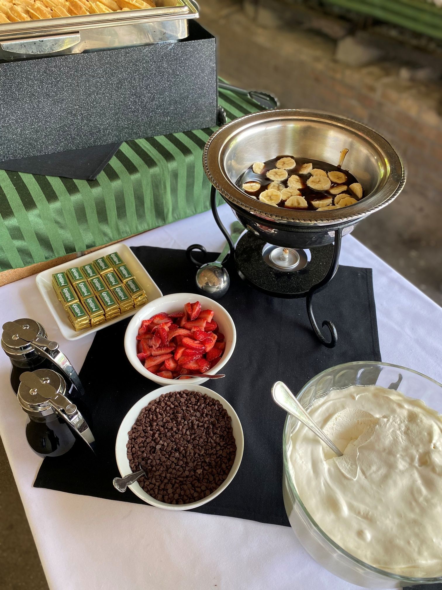 A chocolate fondue setup with dipping items: strawberries, sprinkles, marshmallows, and whipped cream.