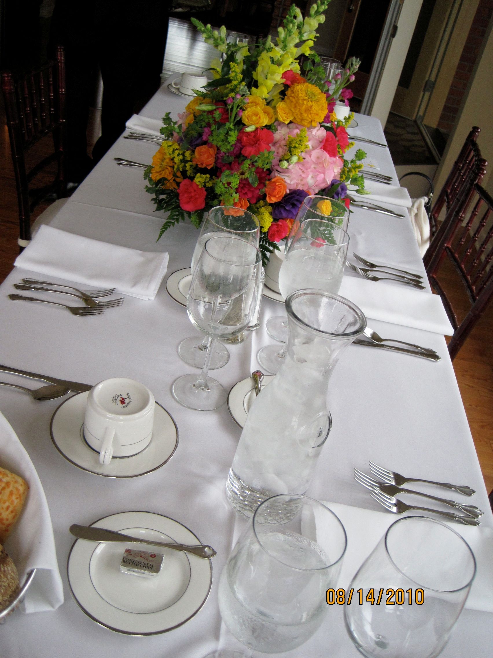 Table set for dining with colorful flower arrangement and glassware.