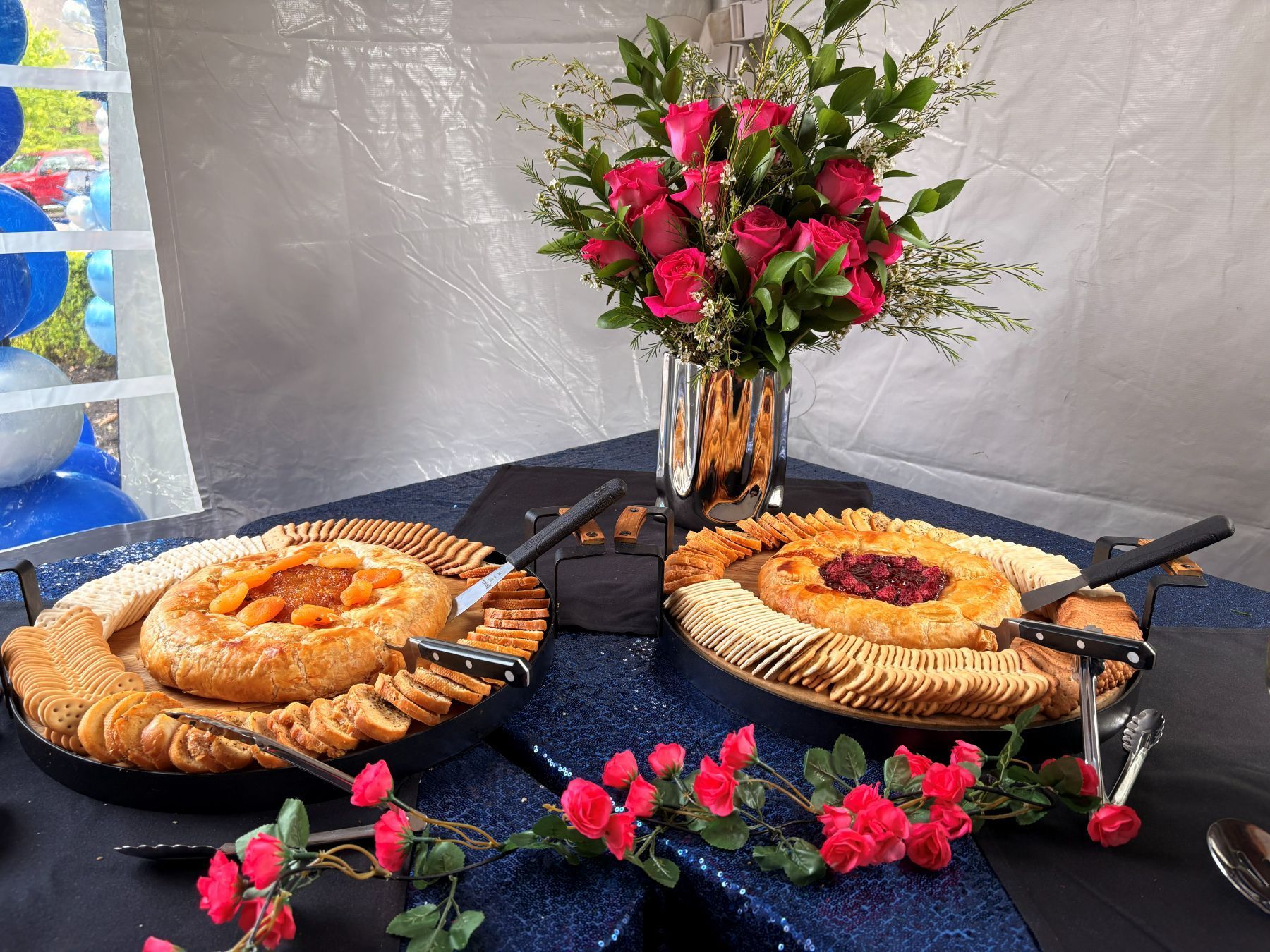 Two appetizer platters with crackers and dips, flowers on a table.
