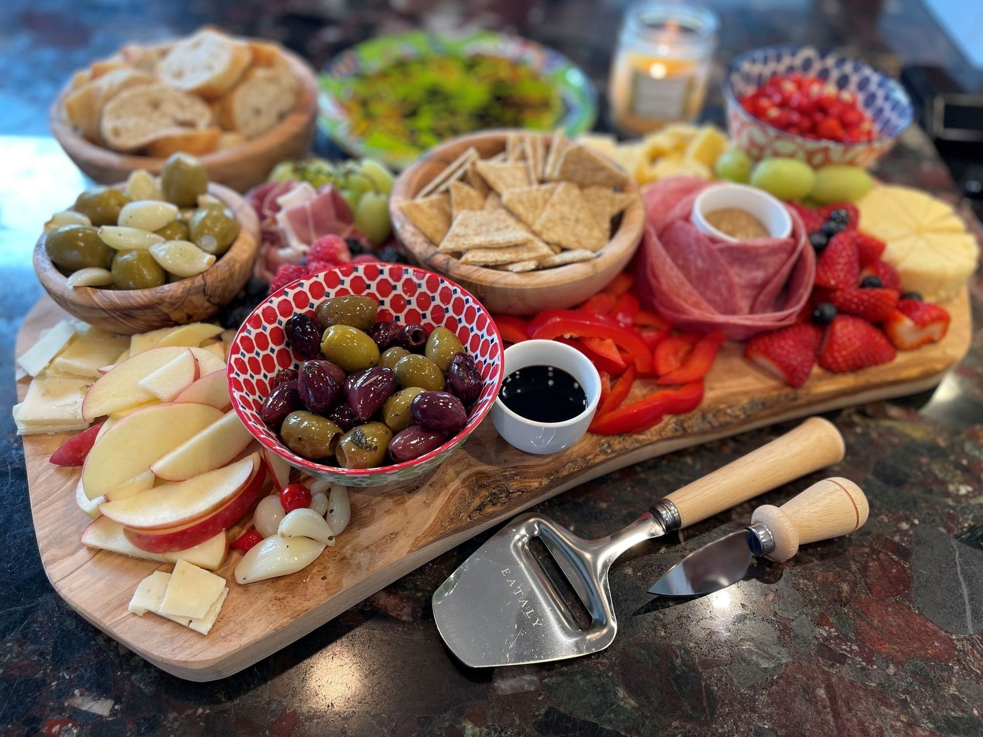 Charcuterie board with various cheeses, fruits, olives, crackers, and meats.